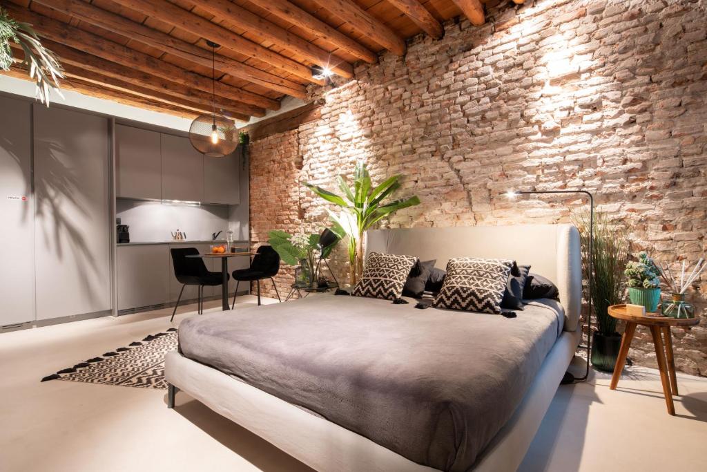una camera con un grande letto e un muro di mattoni di OFFICINE CAVOUR Piazza Cavour a Padova