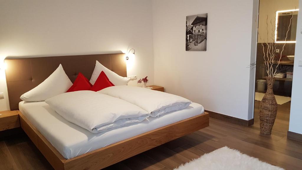 a bedroom with a bed with white and red pillows at Appartements Dornach in Schenna