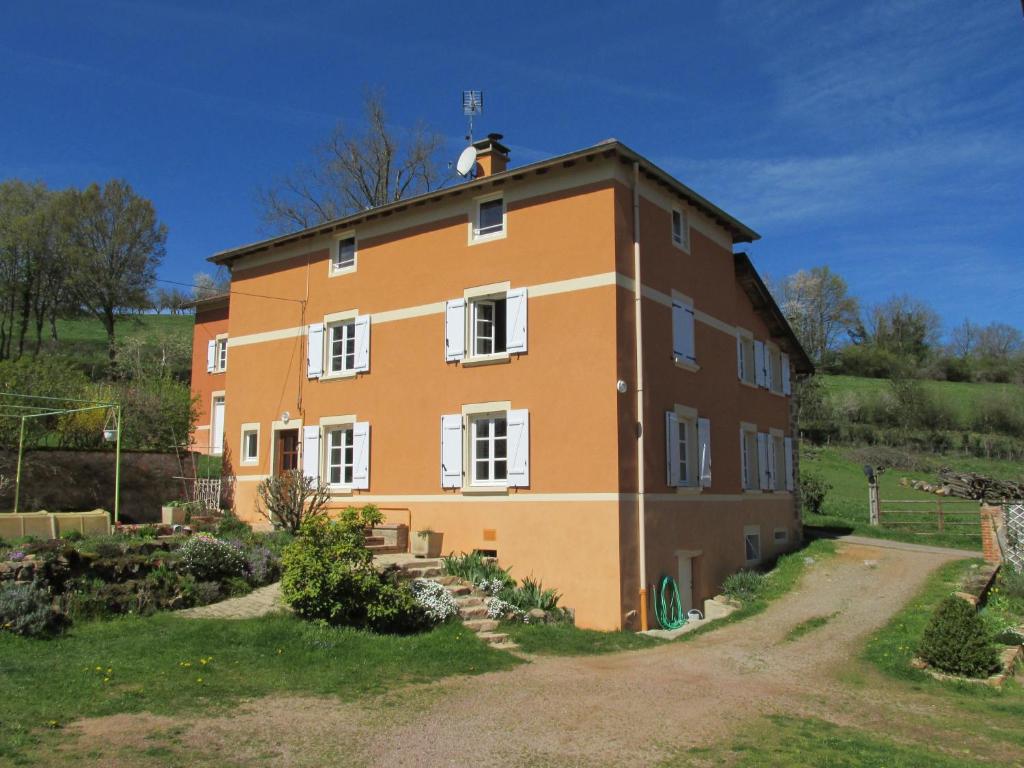 un grand bâtiment orange avec des fenêtres blanches dans l'établissement La vache sur le toit, à Montagny