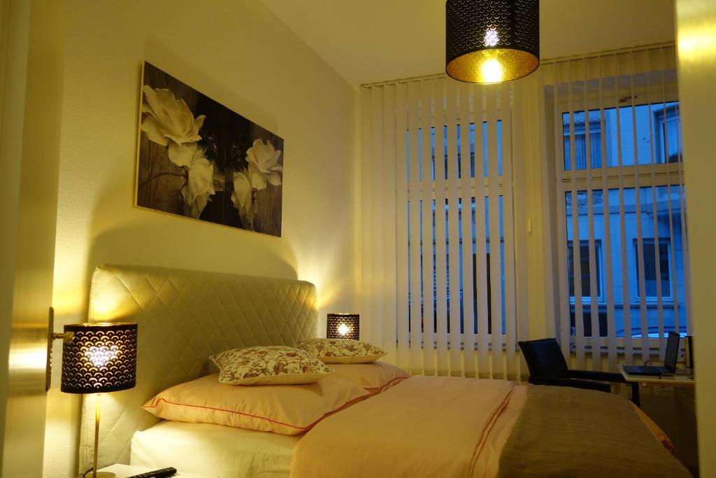 a bedroom with a bed with two lights and two windows at Nettes, gemütliches Apartment in Wuppertal