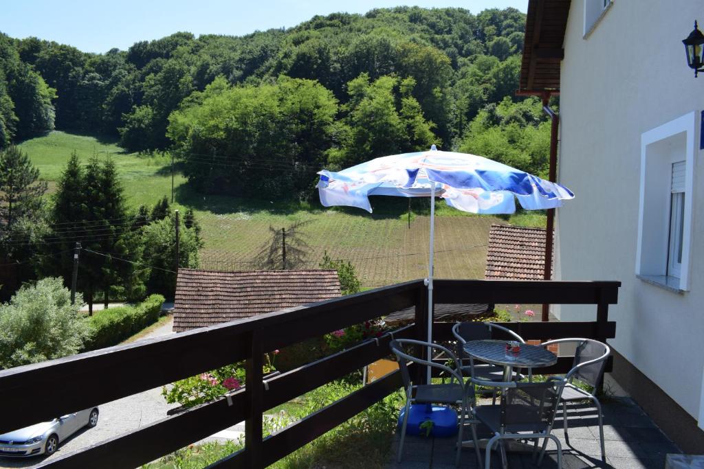 a table and chairs on a balcony with an umbrella at Apartmani Huško in Tuheljske Toplice