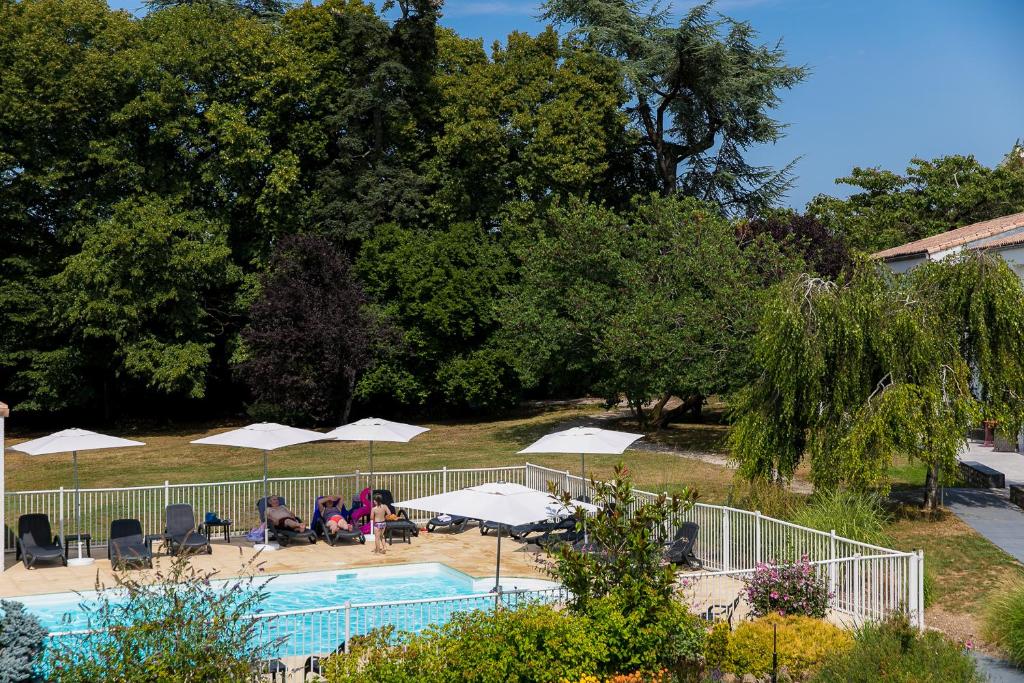 une piscine avec des parasols et des personnes assises autour de celle-ci dans l'établissement Logis LE RABELAIS Hôtel- Restaurant - SPA, à Fontenay-le-Comte