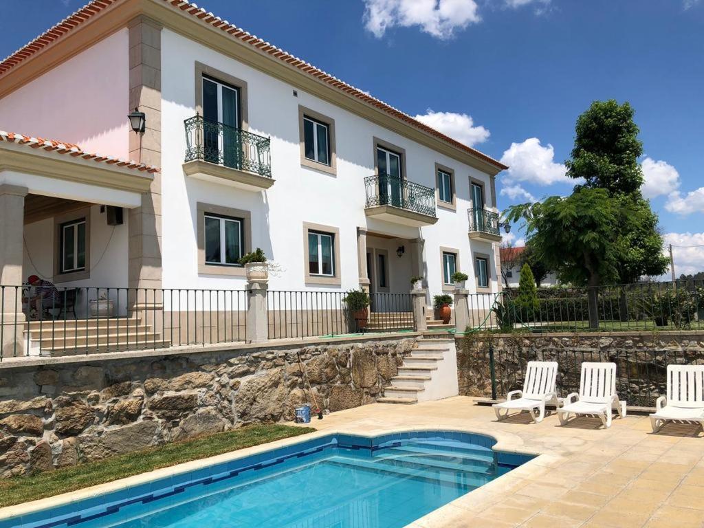 a villa with a swimming pool in front of a house at SOLAR DA SERRA-GuestHouse in Mangualde