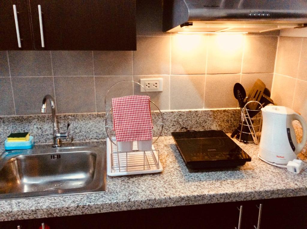 a kitchen counter with a sink and a cutting board at Studio Fully Furnished in Manila