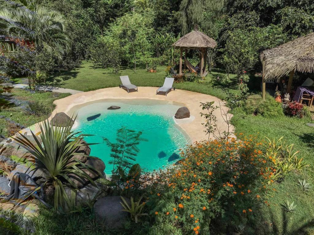 a swimming pool with two chairs and a gazebo at west indies cottage in Pointe-Noire