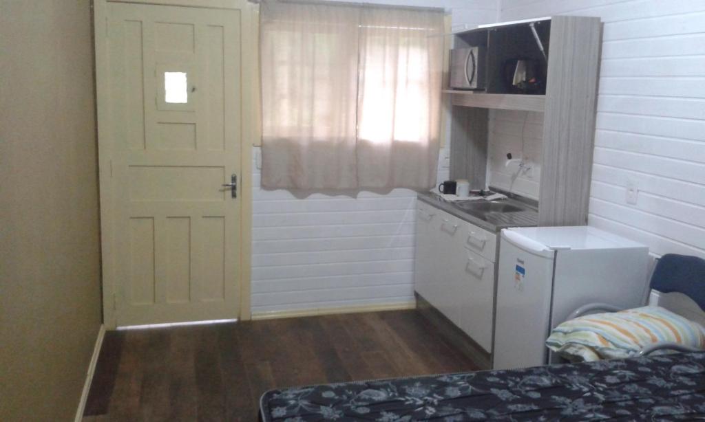 una pequeña cocina con puerta blanca y fregadero en Chalé da Tranquilidade, en Gramado