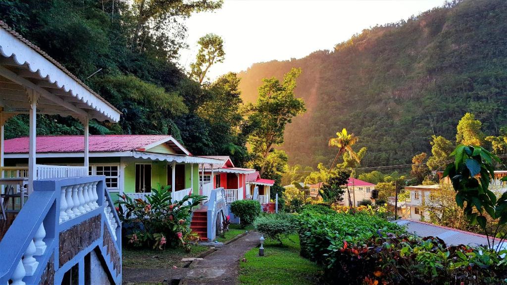 a row of houses in front of a mountain at Chez Ophelia Cottage Apartments in Roseau