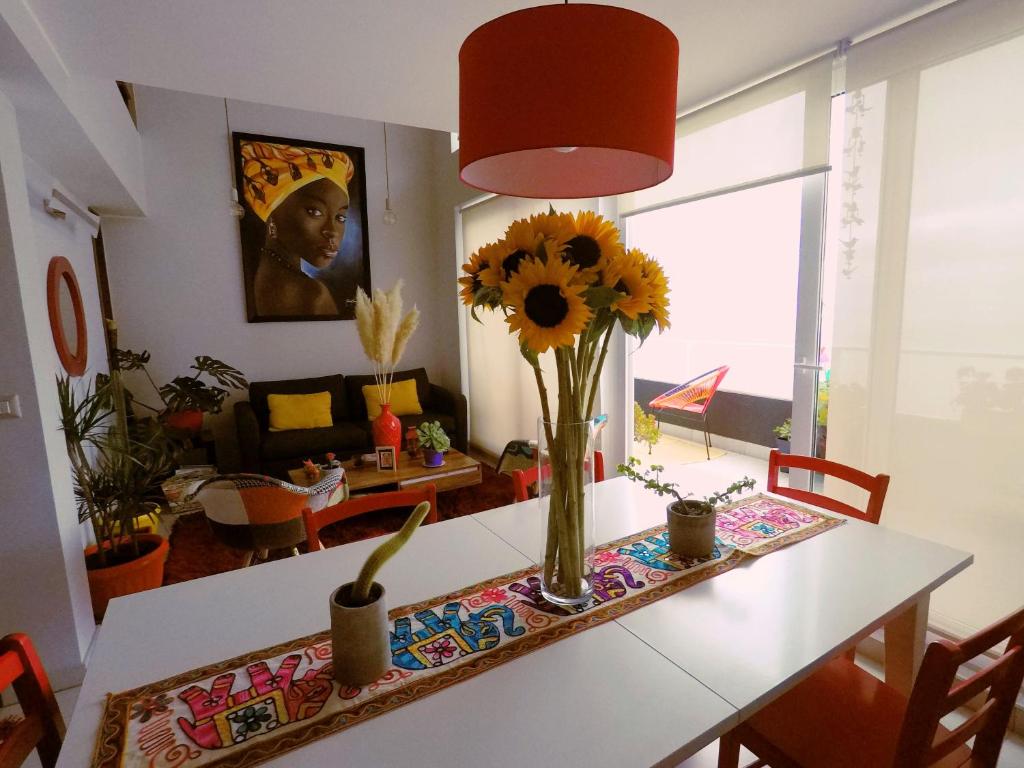 una mesa de comedor con un jarrón de flores. en Loft Reñaca On, en Viña del Mar