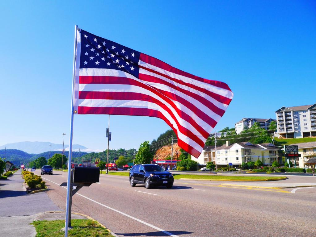 an american flag flying over a road with a car at Americana Inn a Travelodge by Wyndham in Pigeon Forge