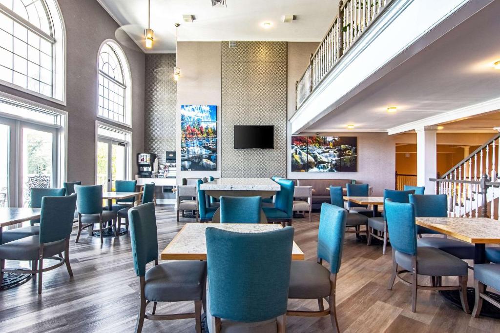 a dining room with tables and blue chairs at Clarion Inn Willow River in Sevierville