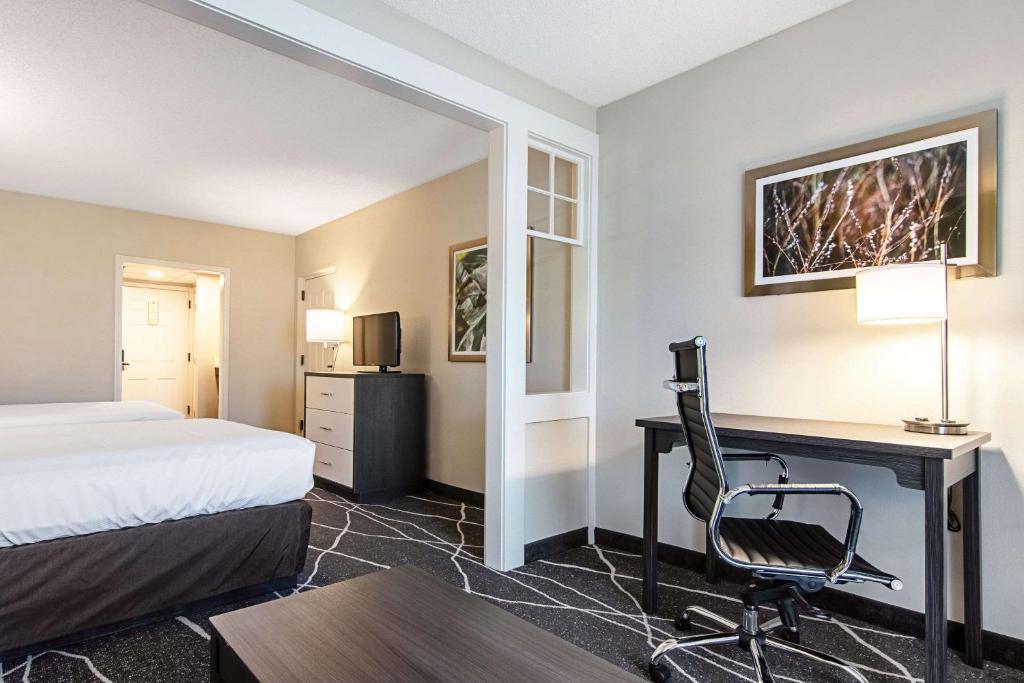 a hotel room with a bed and a desk with a computer at Clarion Inn Willow River in Sevierville
