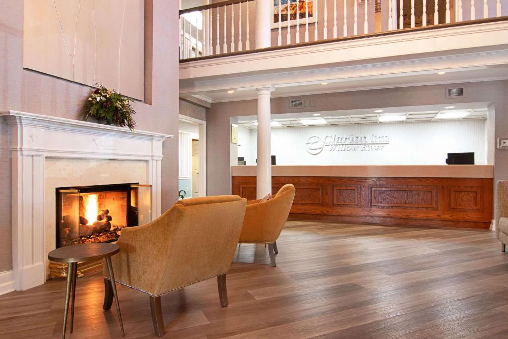 a lobby with chairs and a fireplace and a stage at Clarion Inn Willow River in Sevierville