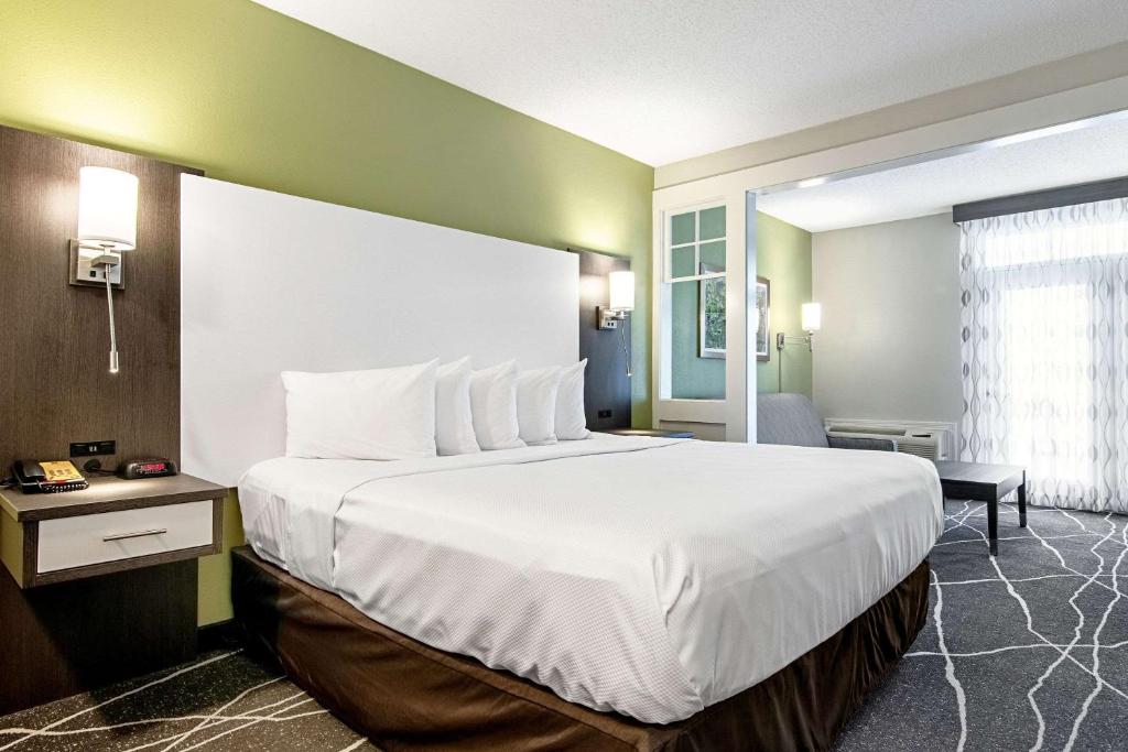 a hotel room with a large bed with white sheets at Clarion Inn Willow River in Sevierville