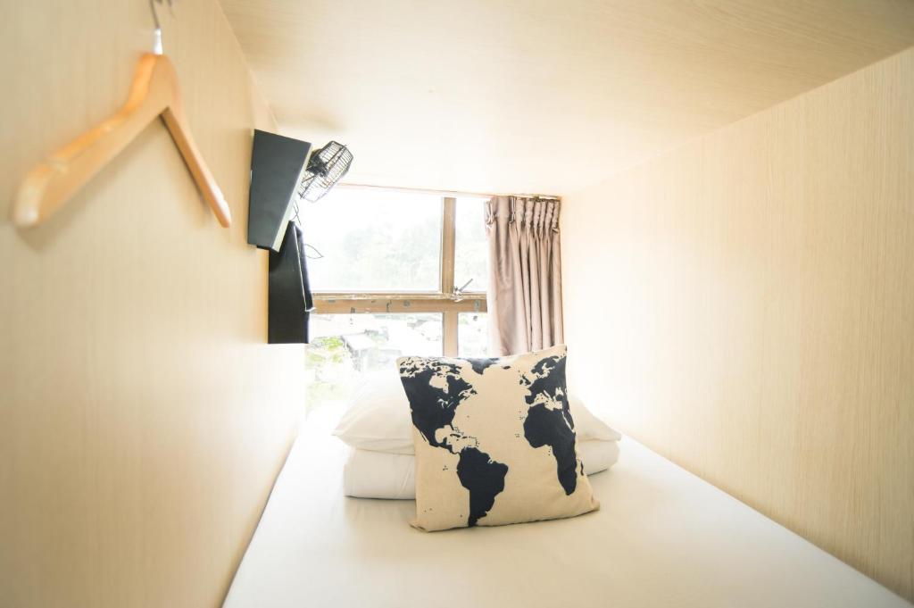 Habitación con almohada de vaca frente a una ventana en Traveller Bunker Hostel, en Cameron Highlands