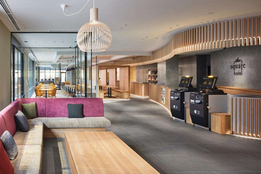 a lobby with a pink couch and a restaurant at the square hotel KANAZAWA in Kanazawa