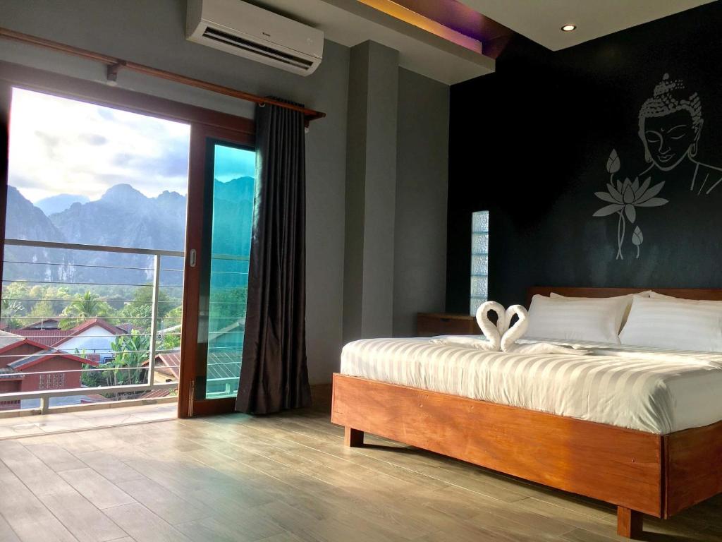 a bedroom with a bed and a large window at FARAWAY SUITES in Vang Vieng