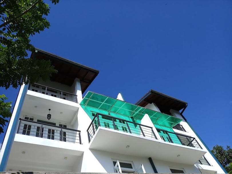 a tall white building with a green roof at Twin Villa 22 in Katugastota