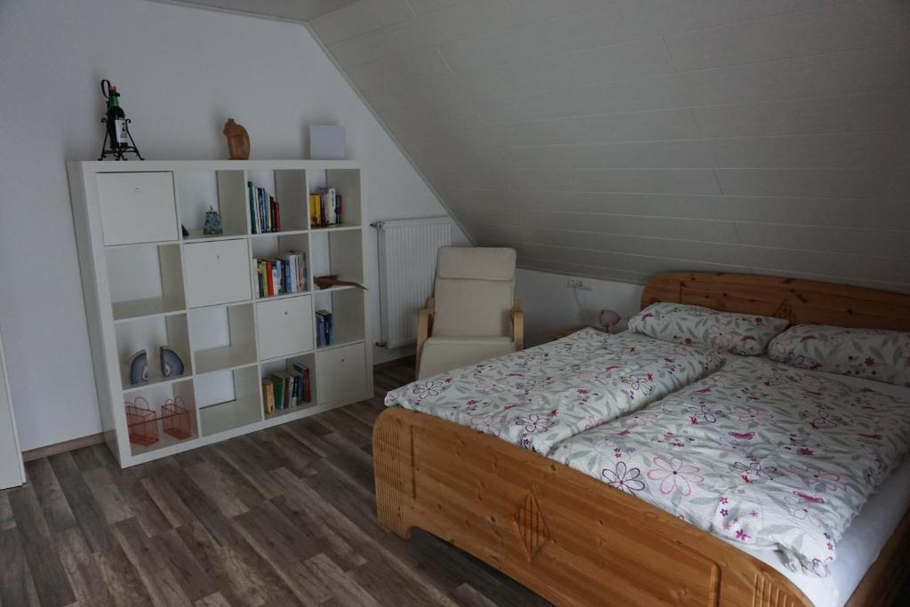 a bedroom with a bed and a chair and book shelves at Fewo Jule in Thaleischweiler-Fröschen