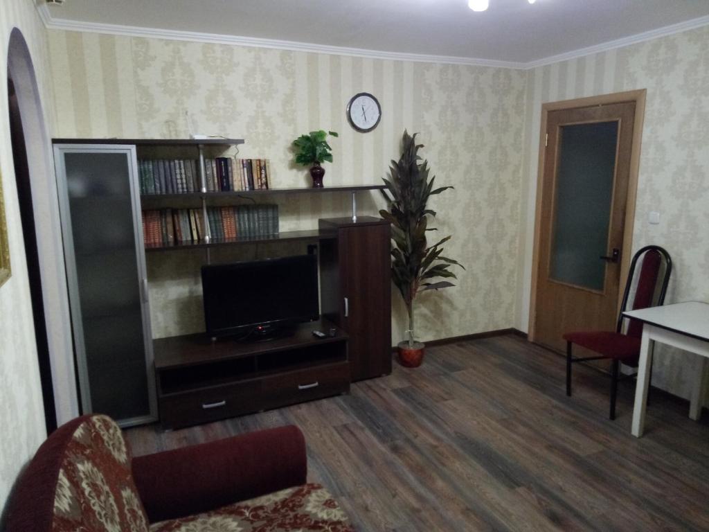 a living room with a television and a book shelf at Hotel Gloria in Cherepovets