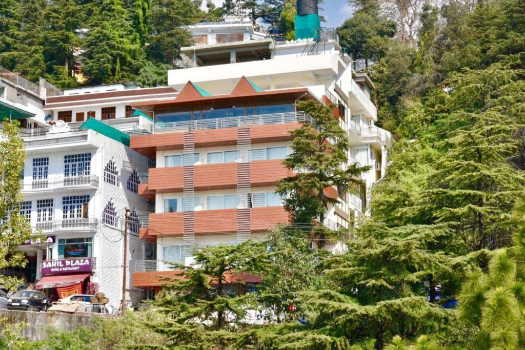 a building on the side of a hill with trees at Citrus Classic Mcleodganj in Dharamshala