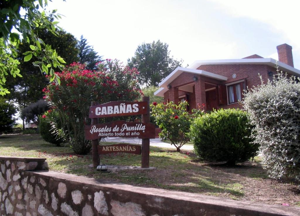 a sign in a yard in front of a house at Cabañas Rosales de Punilla in Huerta Grande