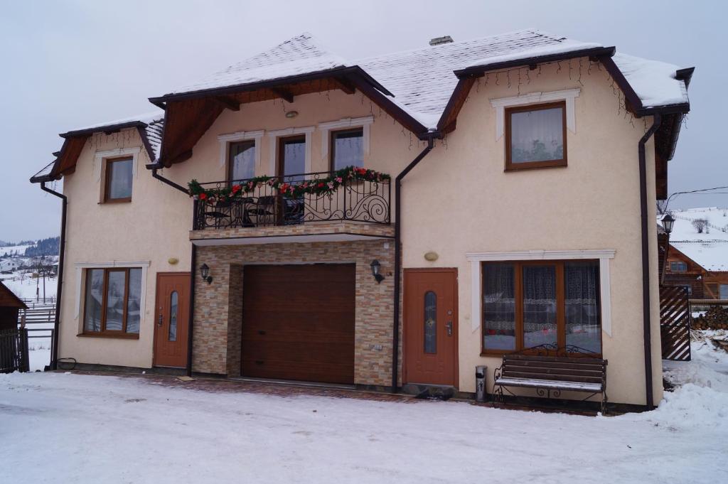 a house with a balcony and a garage in the snow at Panorama Yasinya in Yasinya