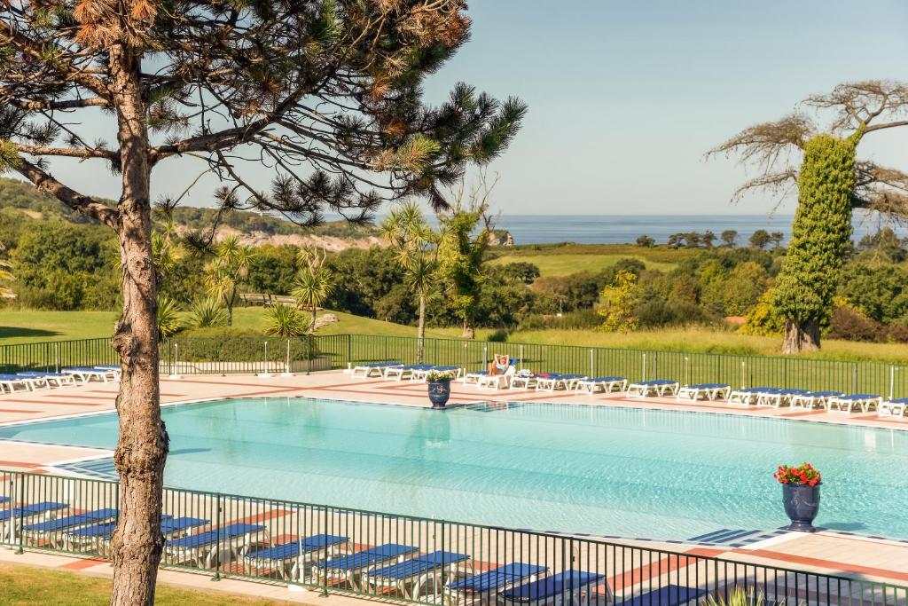 a large swimming pool with chairs and a tree at Résidence Pierre & Vacances Le Domaine de Bordaberry in Urrugne