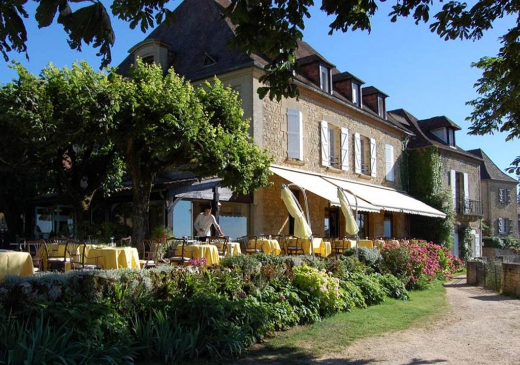 a restaurant with yellow tables and chairs in front of a building at L'Esplanade in Domme