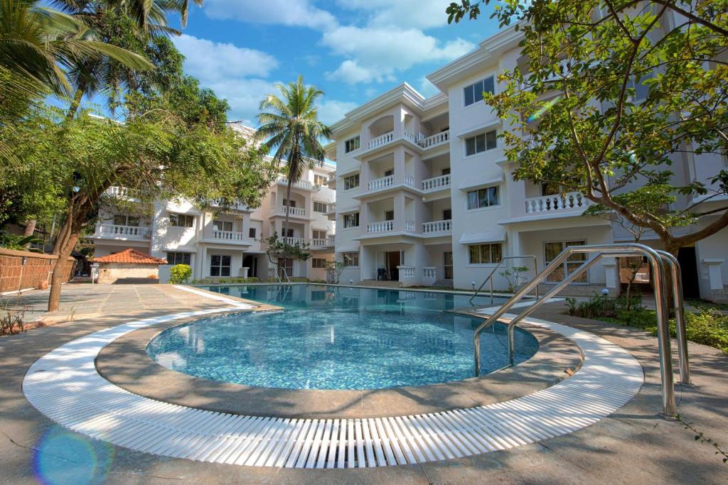 a swimming pool in front of a building at Resort Paloma De Goa in Colva