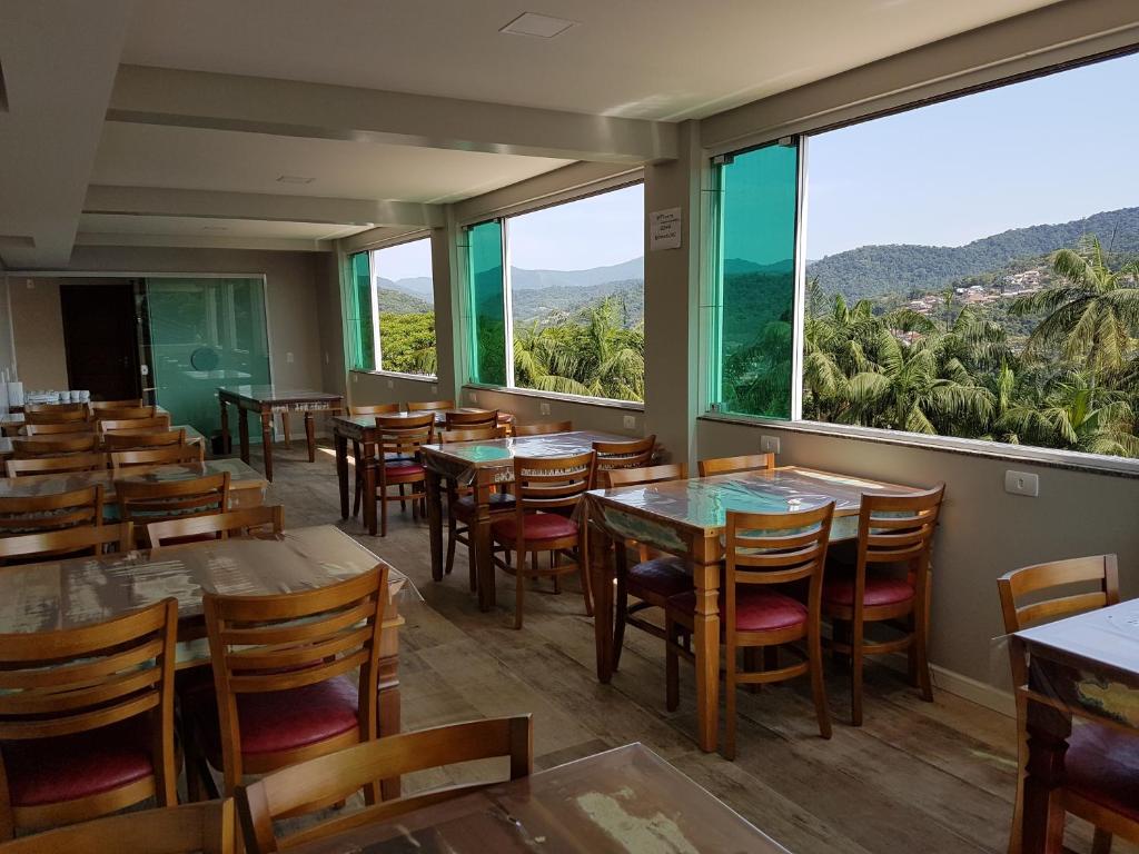 un restaurante con mesas, sillas y ventanas grandes en Pousada Do Galdino, en Blumenau
