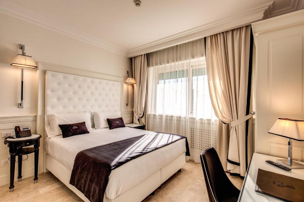 een witte slaapkamer met een bed en een raam bij Hotel Domus Mea in Rome