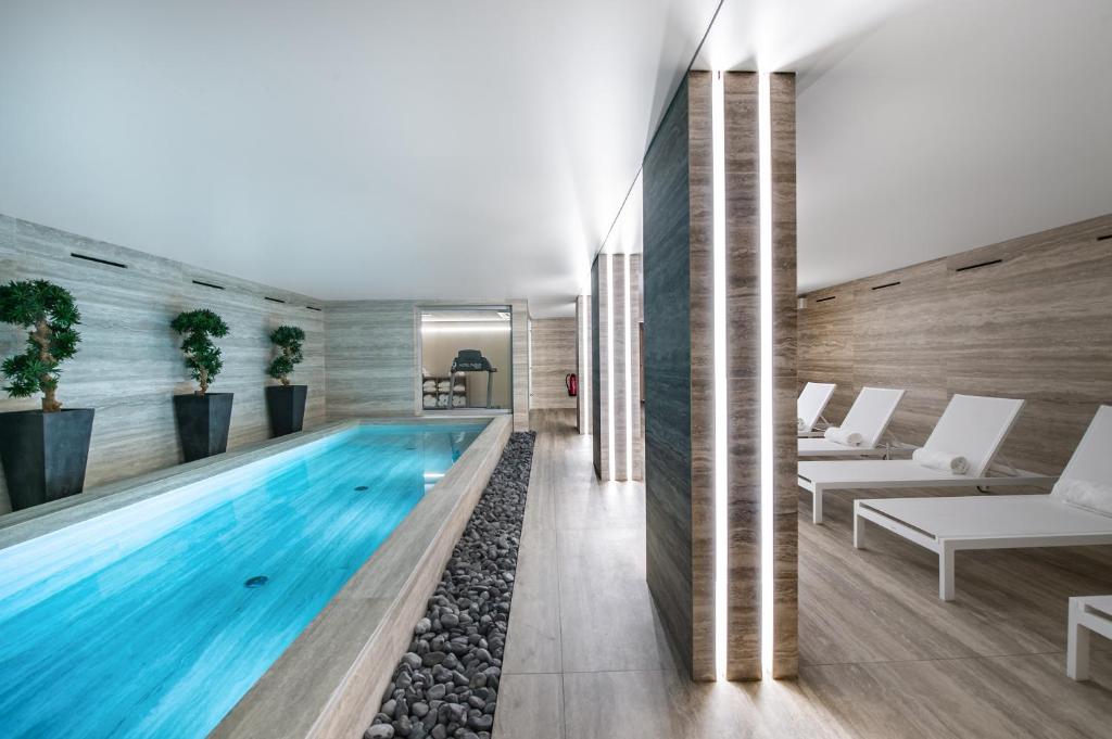 an infinity pool in a house with white furniture at 9Hotel Paquis in Geneva
