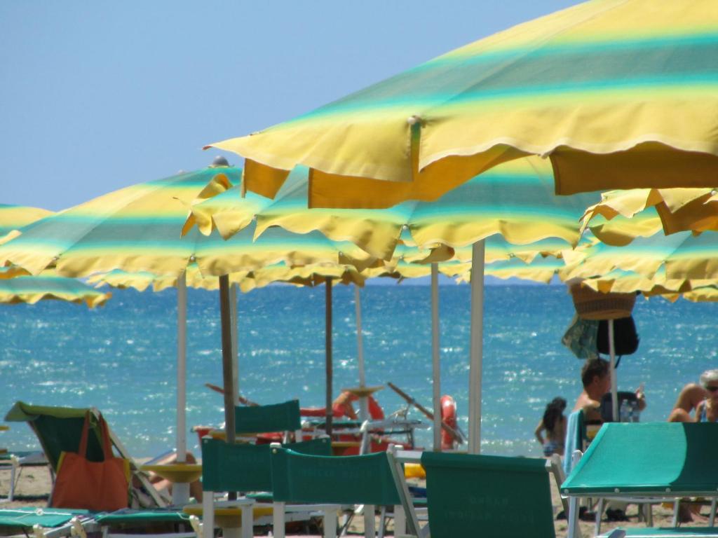 un gruppo di sedie e ombrelloni in spiaggia di Oltremare Appartamenti a Principina a Mare