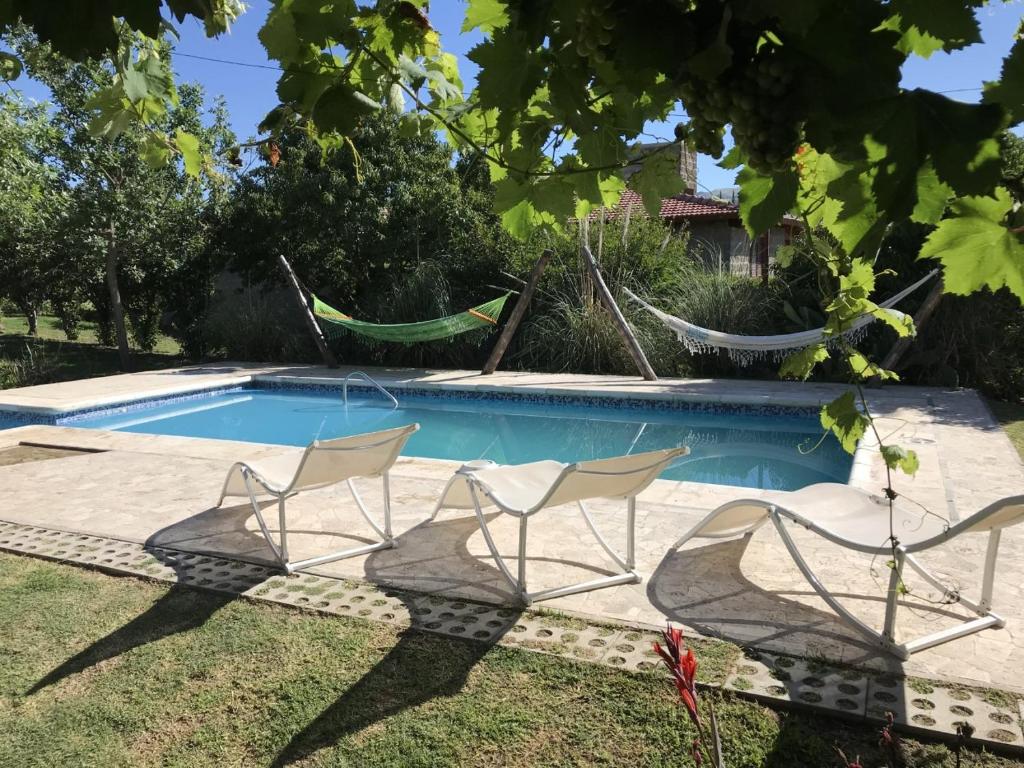 a pool with two chairs and a hammock in a yard at Las Gemelas in Bialet Massé