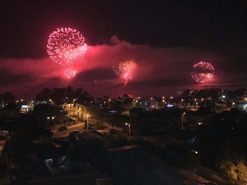 un espectáculo de fuegos artificiales en el cielo sobre una ciudad en Gran departamento con vista al mar, en Concón