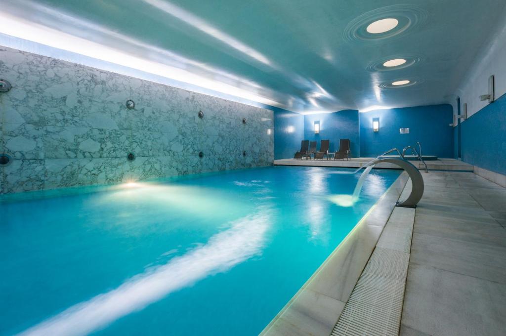 a swimming pool in a hotel with blue lighting at Hotel de Guimaraes in Guimarães