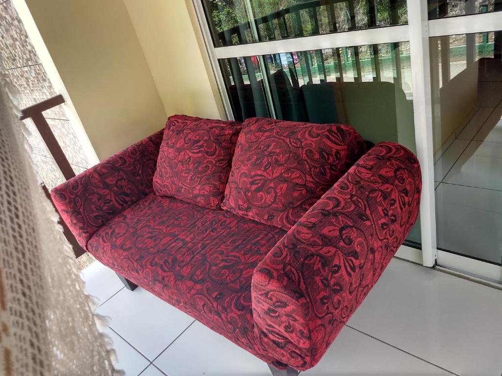 a red couch in a room with a window at Casa das Flores in Guaramiranga