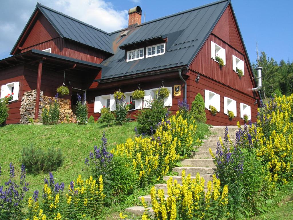 a red house with a black roof and some flowers at Horský Penzion Černava in Horní Malá Úpa