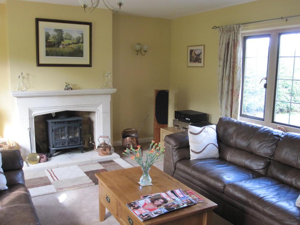 a living room with a leather couch and a fireplace at Pardon Hill Farm B&B in Cheltenham