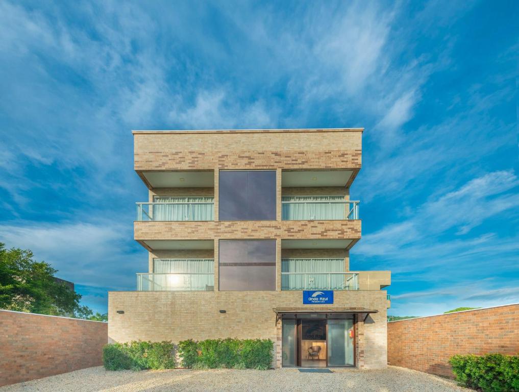 un edificio alto de ladrillo con un cielo azul en el fondo en Residencial Onda Azul en Bombinhas