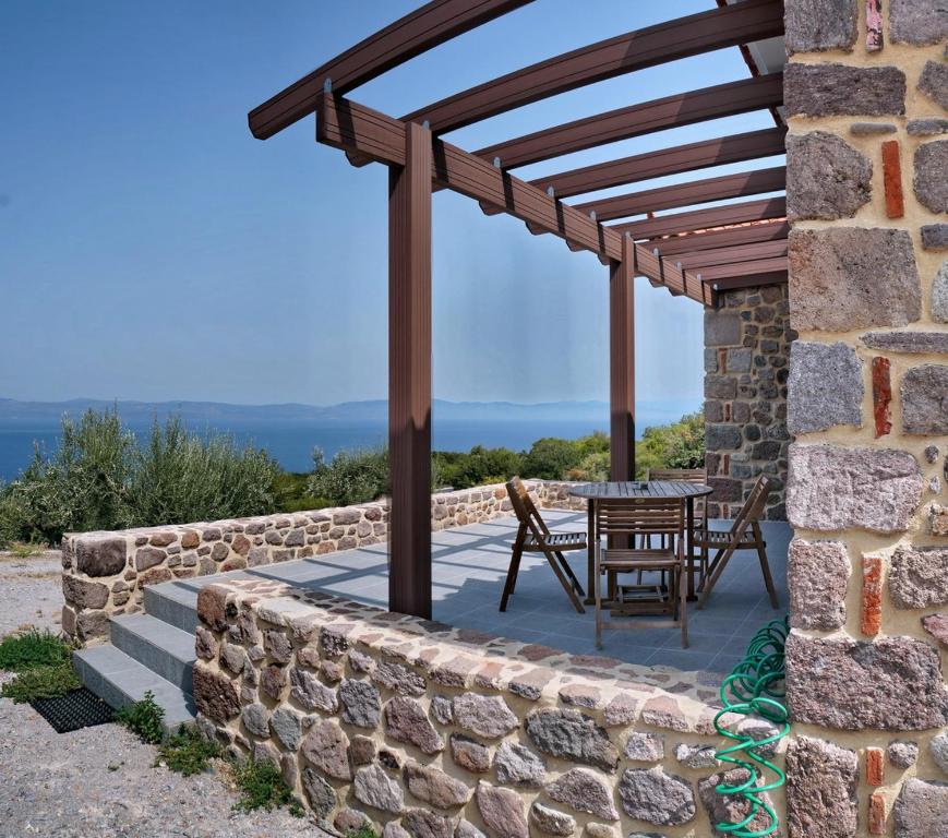 un patio con una mesa y una pared de piedra en Ktima Kiourelioti, en Skála Sykaminéas