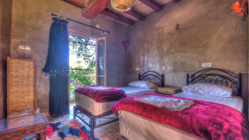 1 dormitorio con 2 camas y ventana en Gite Tamlli, en Aoufous