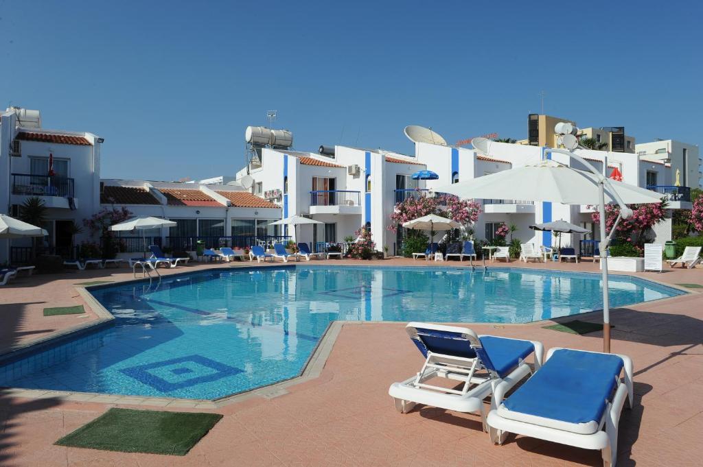 a swimming pool with two lounge chairs and buildings at Alexia Hotel Apartments in Ayia Napa