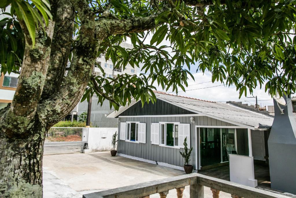 ein kleines Haus mit einem Baum davor in der Unterkunft DK1 - CASA CoM 3 DORM COM PISCINA BRUNO KLEMTZ in Itapema