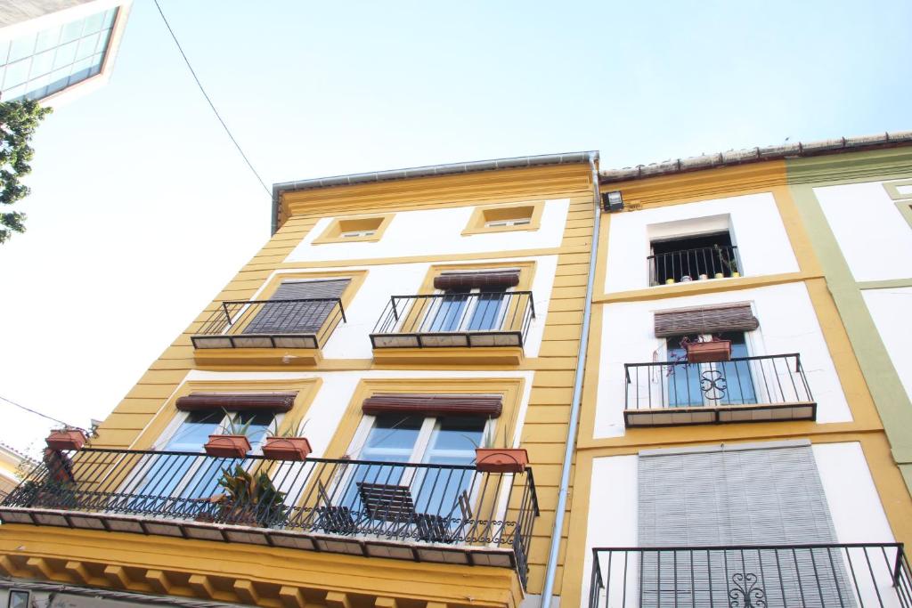 un edificio amarillo con balcones en un lateral en Las Coles Apartasuites, en Xàtiva