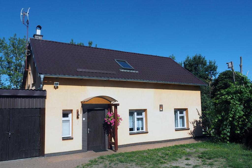 ein kleines weißes Haus mit schwarzem Dach in der Unterkunft Domek na Kaszubach - Cały dla Ciebie! in Lipnica