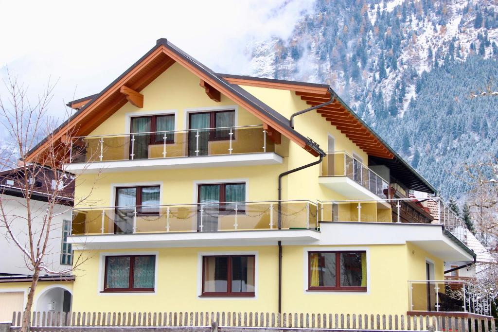 a yellow building with a balcony and mountains in the background at Apartments Davydov in Bad Hofgastein