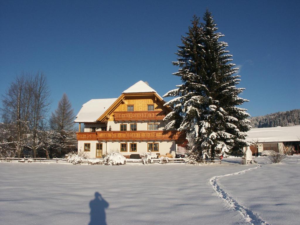 une personne marchant dans la neige devant une maison dans l'établissement Bio Bauernhof Schoberhof, à Sankt Andrä im Lungau