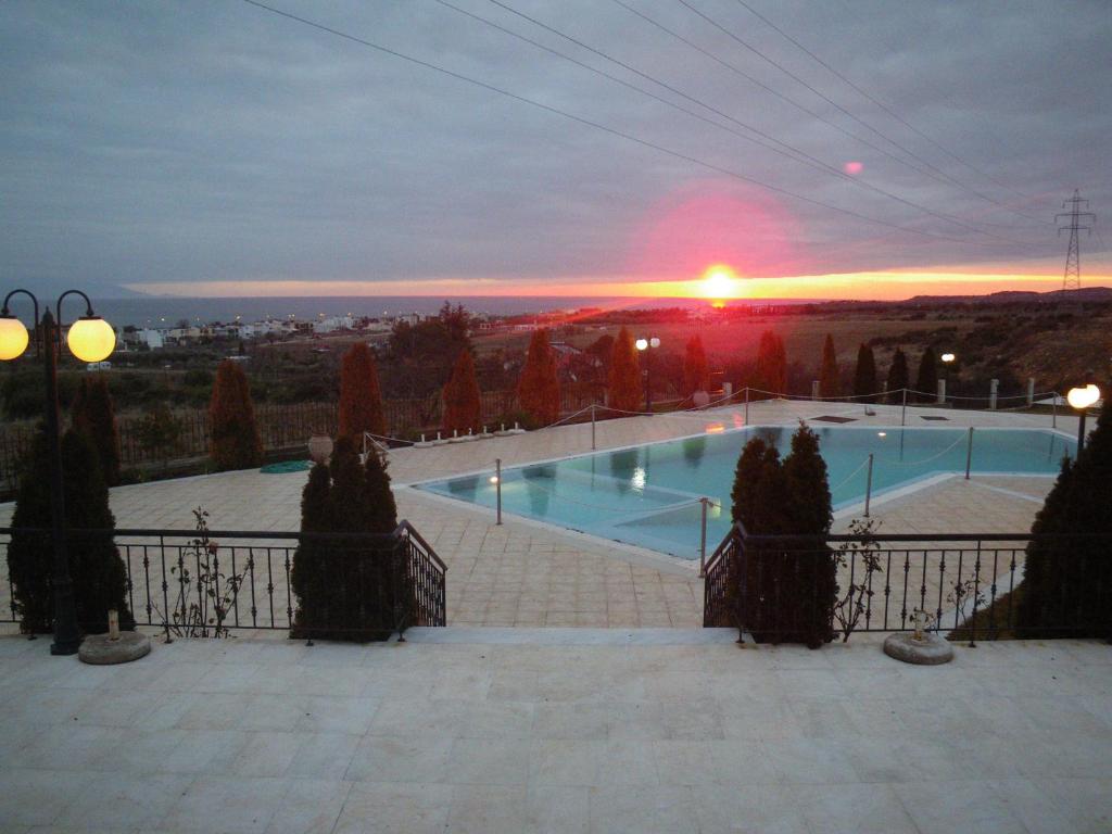 a swimming pool with a sunset in the background at Bell Air Hotel in Alexandroupoli