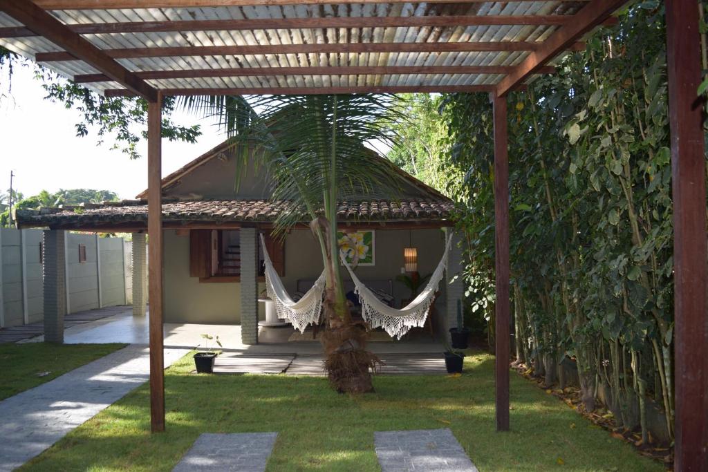 una pérgola con una palmera delante de una casa en Casa 2 Mariane Trancoso, en Trancoso